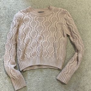 Women’s cable knit sweater in a pink/lavender colour.